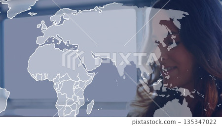 Standing woman wearing business casual inside office with world map overlay and blinds, copy space 135347022