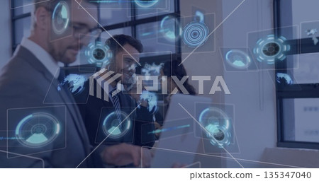 Collaborating professionals in suits using laptop smartphone and holographic screens at office desk 135347040