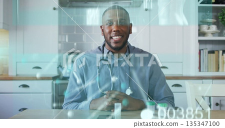 Smiling doctor wearing blue shirt with stethoscope showing pills at kitchen table, medical concept Smiling doctor wearing blue shirt with stethoscope showing pills at kitchen table, medical concept 135347100