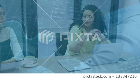 Woman in yellow blouse leading meeting in conference room, with laptop clipboard and stock charts 135347216