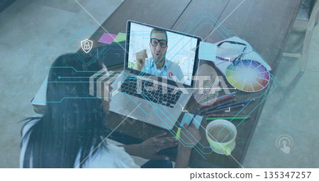 Grasping phone, woman watching colleague speaking on laptop at home desk with overlays, copy space 135347257