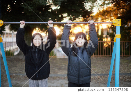 Two sisters, a junior high school student and a high school student, playing happily in a park in a residential area on a winter evening 135347298