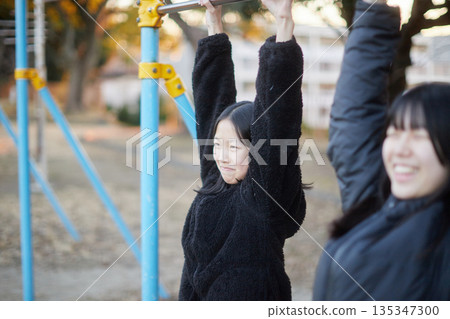 Two sisters, a junior high school student and a high school student, playing happily in a park in a residential area on a winter evening 135347300