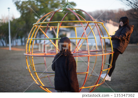 Two sisters, a junior high school student and a high school student, playing happily in a park in a residential area on a winter evening 135347302