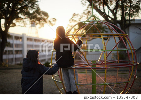 Two sisters, a junior high school student and a high school student, playing happily in a park in a residential area on a winter evening 135347308