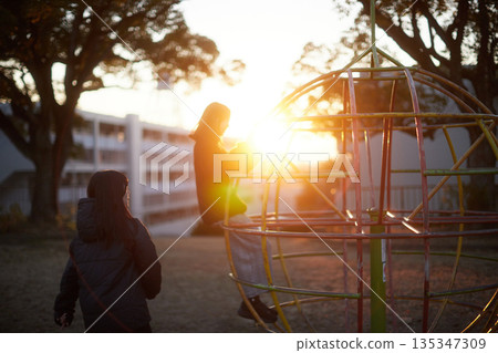 Two sisters, a junior high school student and a high school student, playing happily in a park in a residential area on a winter evening 135347309