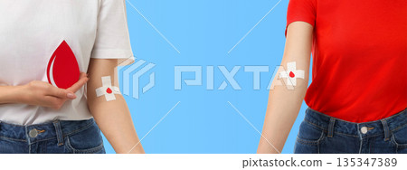 Blood donation from two people showing bandages on arms 135347389