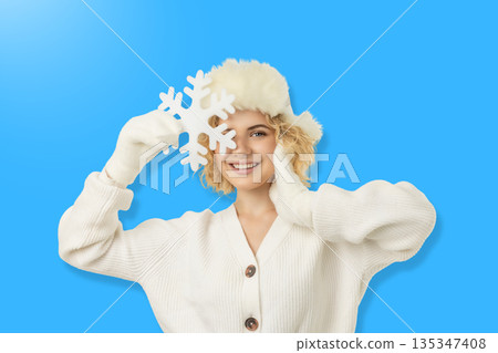 Happy woman in winter wear holds a snowflake Happy woman in winter wear holds a snowflake 135347408
