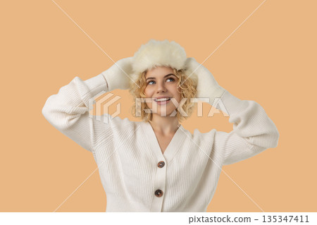 Woman smiling while wearing a white fluffy hat and gloves Woman smiling while wearing a white fluffy hat and gloves 135347411