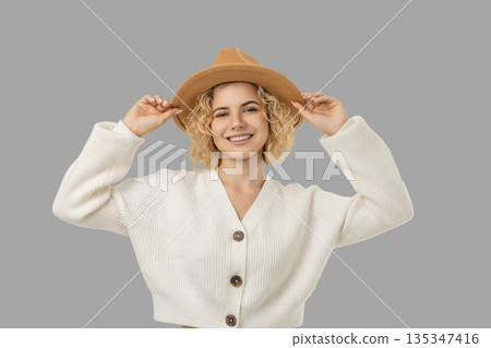 Young woman in a white sweater and tan hat smiling Young woman in a white sweater and tan hat smiling 135347416