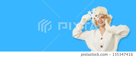 Woman smiling while holding large snowflakes in a bright setting Woman smiling while holding large snowflakes in a bright setting 135347418
