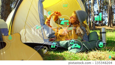 Sharing fruit slice, couple lying at yellow dome tent in forest clearing, with guitar, mug, thermos Sharing fruit slice, couple lying at yellow dome tent in forest clearing, with guitar, mug, thermos 135348204
