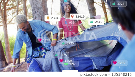 Friends assembling tent holding poles and adjusting fabric at camp among pines, with notifications 135348215