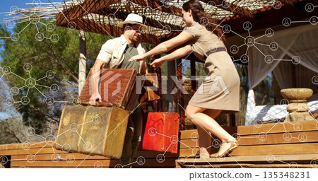 Couple wearing straw hat, beige dress, carrying three vintage suitcases on safari cabin deck 135348231