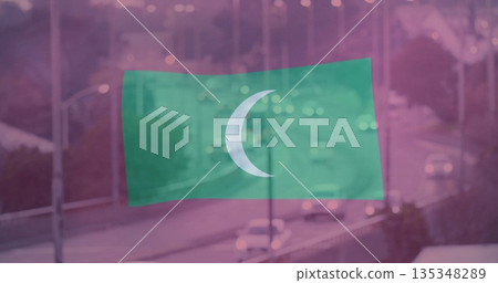 Floating green flag bearing white crescent symbol over road at dusk, with guardrails and car lights 135348289