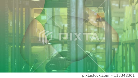 Showing forklift mast and seat standing in warehouse aisle, with pallet racks, cardboard boxes 135348301