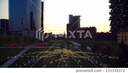 Featuring cityscape showing winding concrete pathways at park at dusk, with colorful bokeh trails 135348372