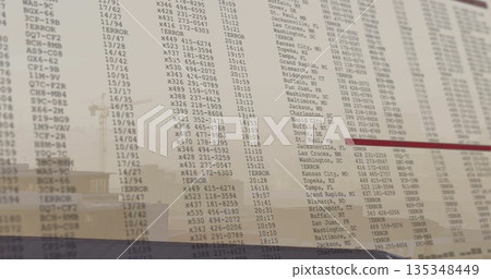 Displaying flight board showing codes and times on glass panel at airport, with building reflection Displaying flight board showing codes and times on glass panel at airport, with building reflection 135348449