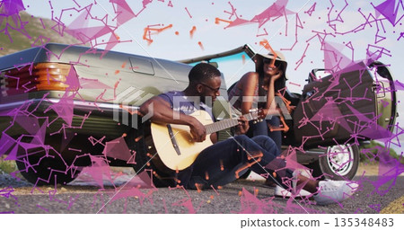 Strumming man and woman smiling on rural roadside, with wood guitar, straw sun hat, convertible car Strumming man and woman smiling on rural roadside, with wood guitar, straw sun hat, convertible car 135348483