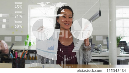 Holding charts, woman wearing business attire showing digital graphics with pencil holder in office 135348484
