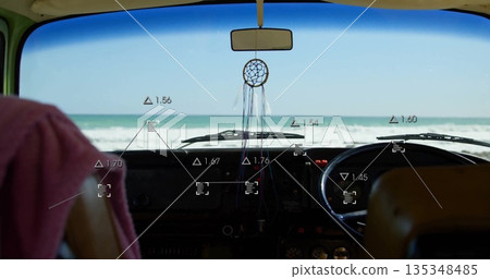 Framing camper van dash showing dreamcatcher hanging from rearview mirror facing beach, with towel 135348485