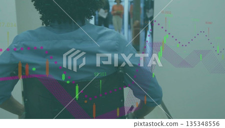 Navigating blue shirt wheelchair user moving through corridor, with glass doors, candlestick charts 135348556