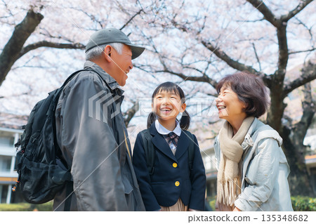 一位笑容燦爛的一年級小女孩告訴她的祖父母，她將在櫻花盛開的背景下入學。 135348682