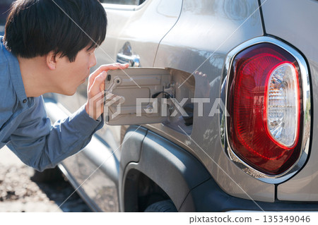 A man checking the fuel tank of his car 135349046