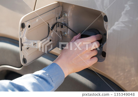 A man checking the fuel tank of his car A man checking the fuel tank of his car 135349048