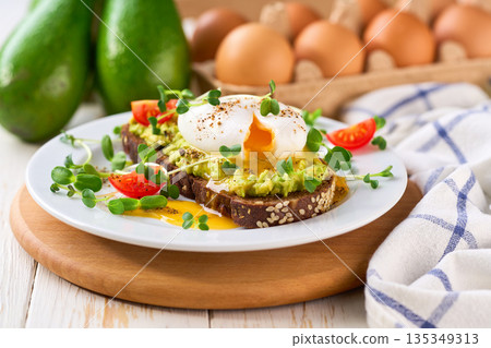 Breakfast with poached egg toast with avocado and tomatoes vegetarian food. Breakfast with poached egg toast with avocado and tomatoes vegetarian food. 135349313