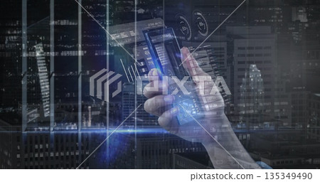 Holding smartphone in light blue sleeve at highrise window at night with holographic charts Holding smartphone in light blue sleeve at highrise window at night with holographic charts 135349490