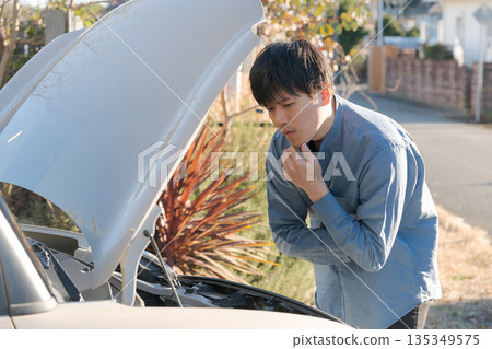 A man opening the hood of a car 135349575