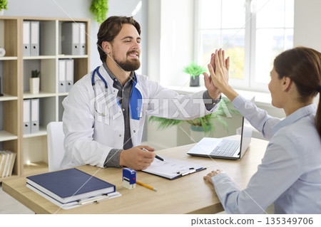 Smiling doctor and patient give high five during consultation in clinic office Smiling doctor and patient give high five during consultation in clinic office 135349706
