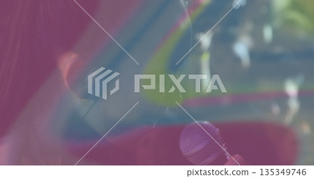 Singing performer holding microphone, wearing in ear monitor on stage with pink blue yellow panels Singing performer holding microphone, wearing in ear monitor on stage with pink blue yellow panels 135349746