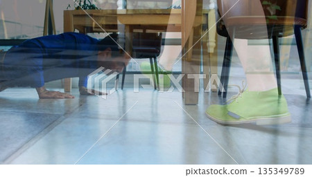 Man in blue shirt performing push-up on tile floor under table, with green shoes, copy space 135349789
