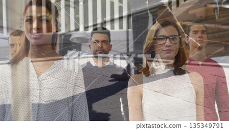 Posing office professionals behind glass partition in office, with pendant lights and desk lamp 135349791