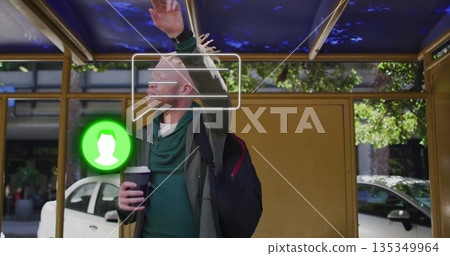 Man in hoodie raising arm waiting bus at gold-framed shelter, with coffee cup, icons, copy space 135349964