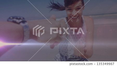 Running mid adult woman wearing sundress holding hand on beach, with wristwatch, sunscreen streak 135349987