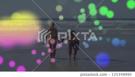 Running couple holding hands at beach shoreline, with yellow bikini, swim trunks and bokeh 135349995