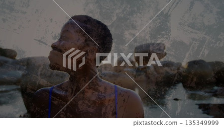 Standing woman in tidal water at rocky cove gazing toward large boulders, with blue swimsuit straps Standing woman in tidal water at rocky cove gazing toward large boulders, with blue swimsuit straps 135349999