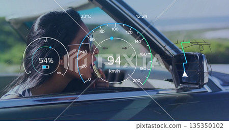 Applying lipstick Indian woman in aviator sunglasses driving convertible by coast, with HUD overlay 135350102