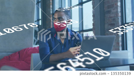 Analyzing man in red mask using laptop and smartphone in coworking lounge with numerical overlays Analyzing man in red mask using laptop and smartphone in coworking lounge with numerical overlays 135350139