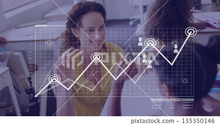 Gesturing teacher wearing yellow blouse teaching kids in classroom, with laptops and graph overlay 135350146