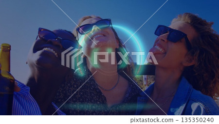Smiling friends wearing sunglasses and necklaces leaning on rooftop terrace, holding beer bottle 135350240