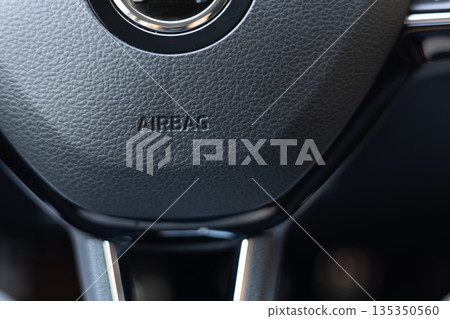 Close view of a car steering wheel with an airbag indicator near a road 135350560