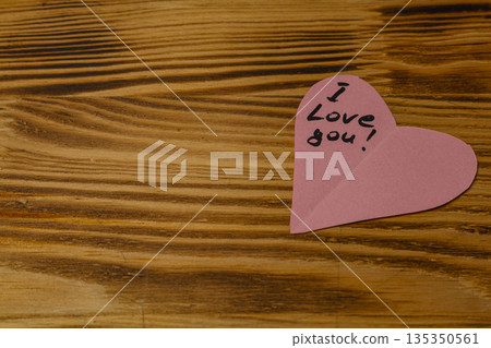 Heart-shaped note with message on wooden surface 135350561