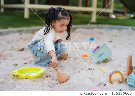 happy child girl playing sand with toy on playground happy child girl playing sand with toy on playground 135350606