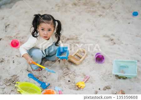 happy child girl playing sand with toy on playground 135350608