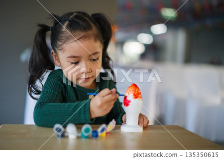 child girl painting plaster statue on table 135350615