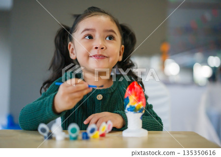 child girl painting plaster statue on table child girl painting plaster statue on table 135350616